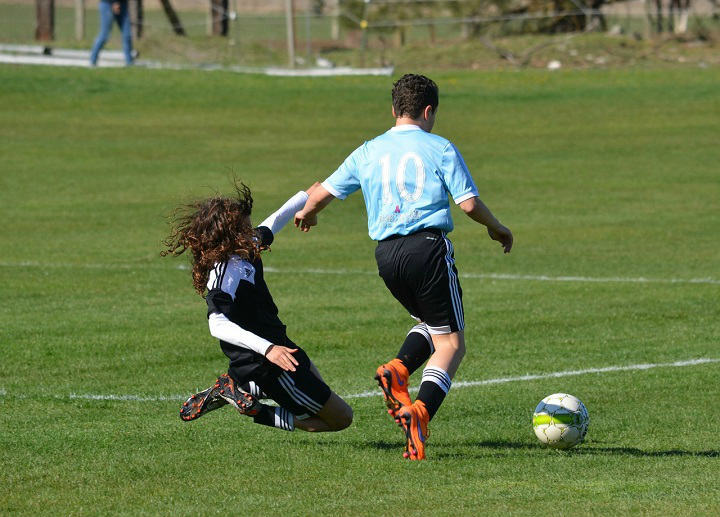boy performing a slide tackle during a soccer game