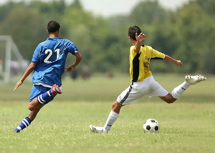 soccer player shooting with defender chasing