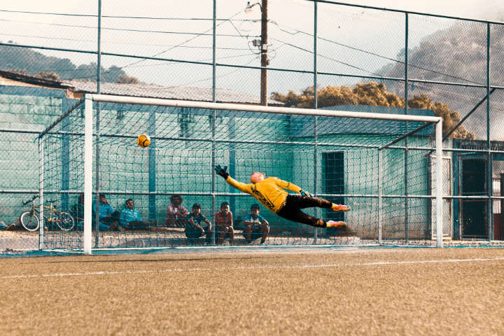 soccer ball going past the goalkeeper into the goal