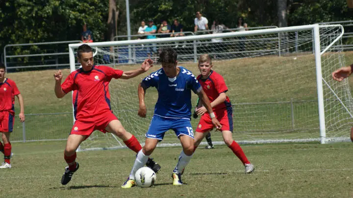 soccer player in red jersey playing defense on blue jersey opponent with soccer ball