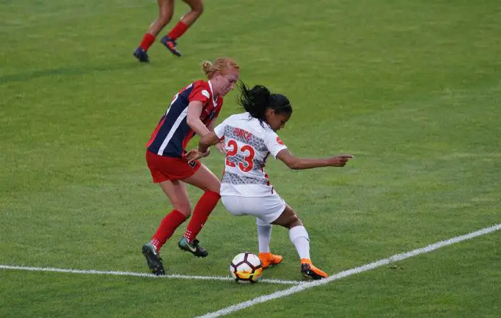 soccer girls in red and white jerseys playing game