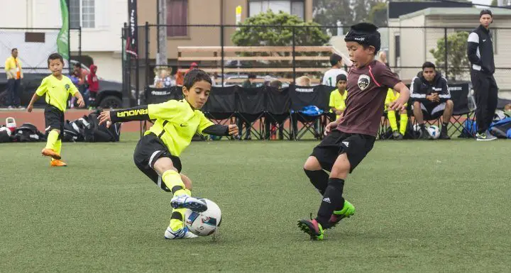 boy controlling a soccer ball during game