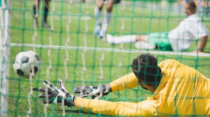 Back view of a goalkeeper catching the ball during a soccer match on the pitch