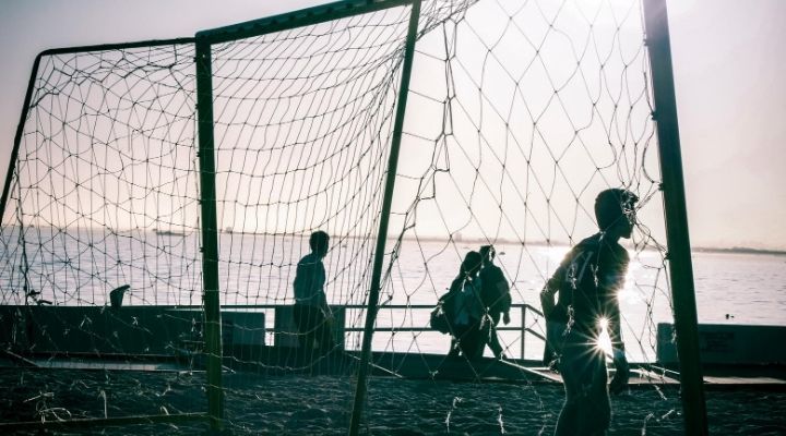 Silhouette of a goalkeeper and a goalpost during sunset beside the beach 