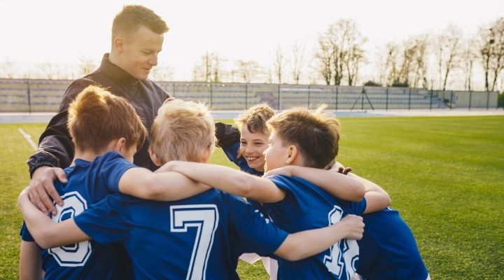 A group of young soccer players huddling in celebration with their coach