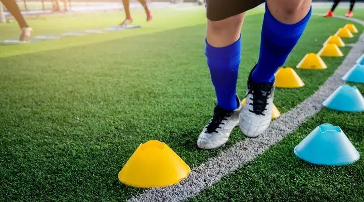 Soccer player jogging and jumping between yellow cone markers during soccer practice
