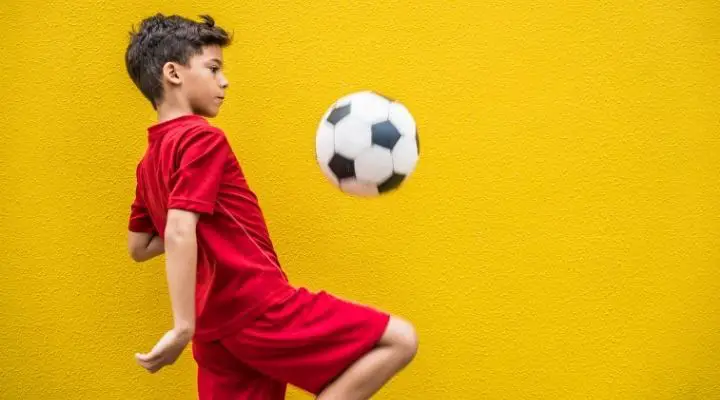 A boy hitting the soccer ball with his knee