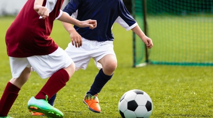 Two kids running after the ball during soccer practice