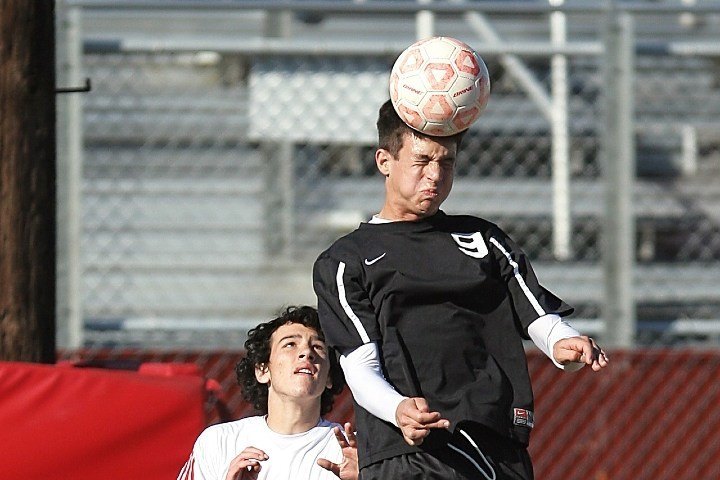 soccer player in black jersey heading ball