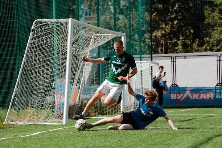 Soccer-player-in-blue-shirt-sliding-under-man-wearing-green