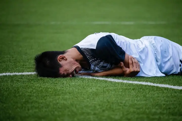 Injured-soccer-player-on-the-ground-holding-elbow-in-pain