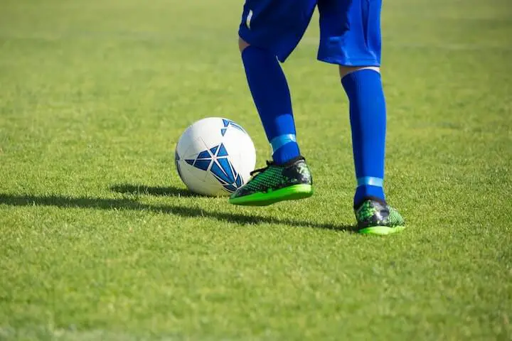 youth-soccer-player-in-green-cleats-dribbling-a-soccer-ball