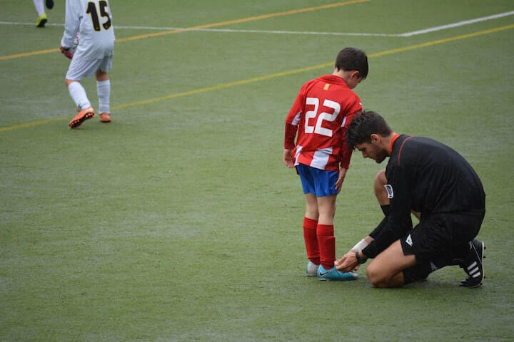 soccer-shin-guard-size-guide soccer-coach-helps-youth-player-with-his-shin-guard