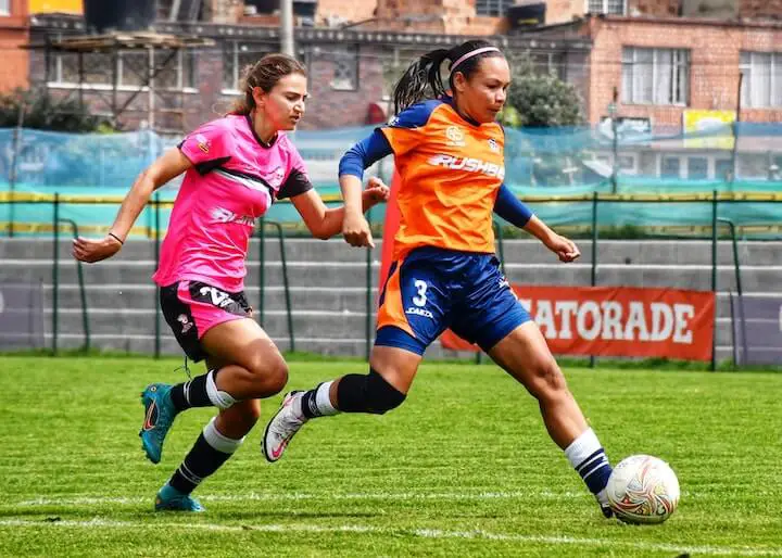 female soccer player dribbles the ball past the defender during a football match