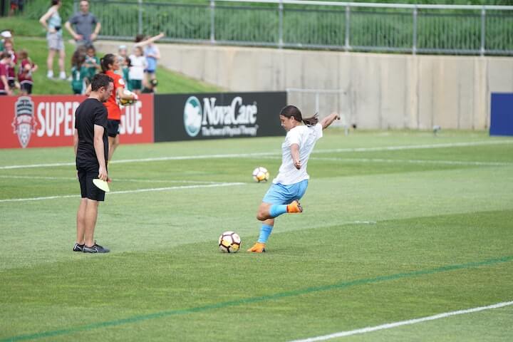 female soccer player practices shooting a soccer a ball with power and accuracy