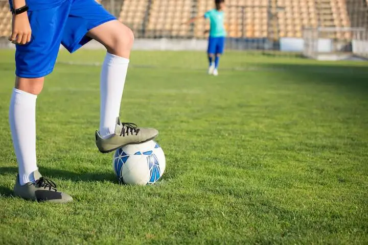player with soccer cleats stepping on soccer ball before attempting a kick